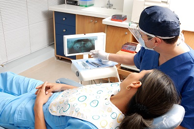 Zahnarzt und Patientin schauen sich ein Röntgenbild an um Karies zu finden