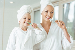 Mother and daughter brush their teeth